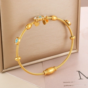 Golden evil eye cuff bracelet with heart pendants on a textured gift box