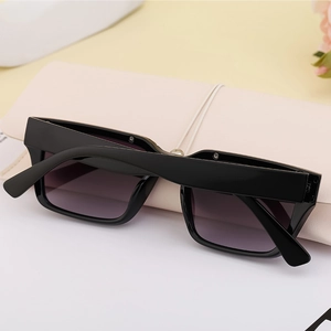 Detail of square black frame sunglasses featuring purple gradient lenses and wide temples