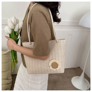 Detail of summer straw tote bag featuring a sunflower accent and rope handle design