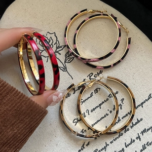 Detailed view of large leopard print hoop earrings in red, pink, and brown tones