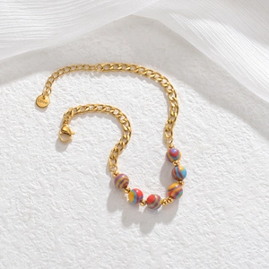 Macro detail of gold-plated stainless steel chain with colorful striped resin beads