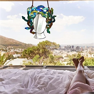Medusa stained glass suncatcher hanging by a window with scenic city sunlight view