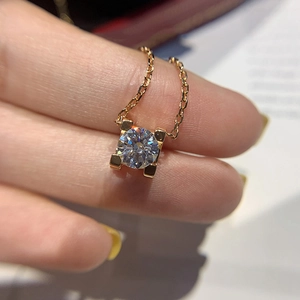 Macro shot of gold-plated necklace pendant with C-shaped prong setting and clear zircon