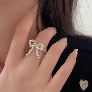 Detailed view of an elastic silver bead ring with a bow design worn by a female model