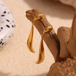 Detailed view of irregular 18K gold plated teardrop earrings on a wooden branch stand
