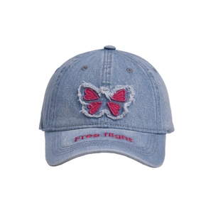 Detail of blue washed denim cap featuring pink butterfly patch and raw edge frayed design