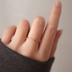 Minimalist gold titanium steel ring with three small zircons on a model's hand