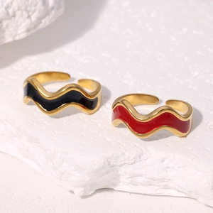 Macro shot of wave-shaped 18k gold plated adjustable rings with black and red enamel inlay