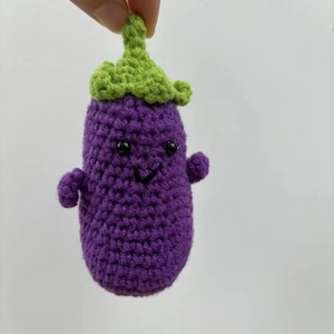Detail of a handmade crochet eggplant plush with cute facial expression and knitted texture