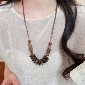 Detail of bohemian necklace with wood beads and dark brown floral pendant discs
