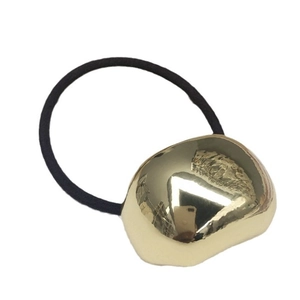 Elastic black hair tie with irregular gold metallic block on a clean white background
