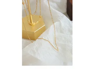 Close-up of layered 18K gold-plated necklaces with Good Luck engraved round pendant