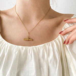 Minimalist gold plated stainless steel T-bar necklace on a female model neck
