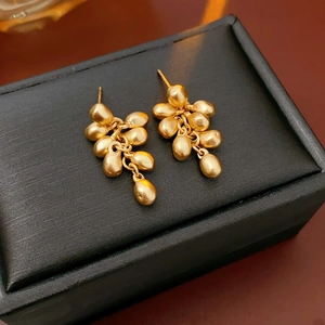 Detailed view of gold drop tassel earrings on a black jewelry box with natural lighting
