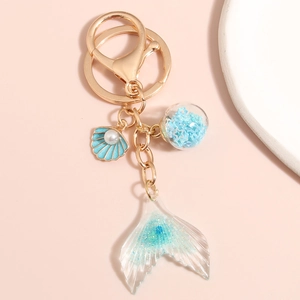 Detail view of ocean mermaid tail keychain with blue glitter and starry glass ball charm