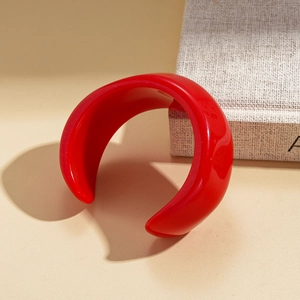 Macro shot of wide-band red resin bangle with glossy finish on minimalist display