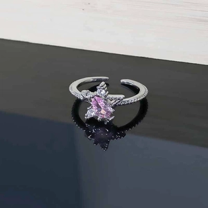 Close-up of star zircon ring with pink marquise gemstone on a reflective black surface