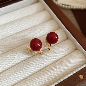 Detail of red round pearl ear clips with golden metal clamps in a jewelry box