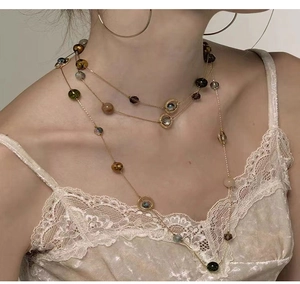 Close-up of layered gold necklace with colorful beads on model showing vintage french style