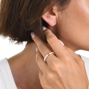 Detail of beaded pearl ring with a single golden steel bead on female model hand
