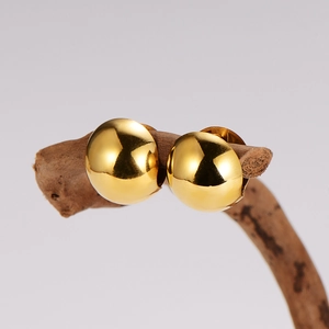 Polished gold dome earrings on wooden stand against a light gray background