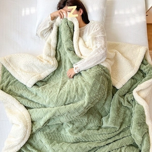 Green knitted double-layer blanket with soft white sherpa fleece lining on a cozy bed