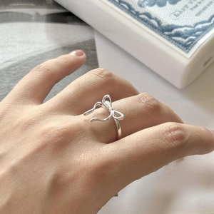 Detail of silver bow ring on hand with elegant lifestyle background setting