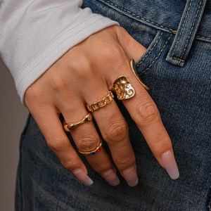 Detail of four-piece gold metal ring set featuring chain link and irregular geometric designs