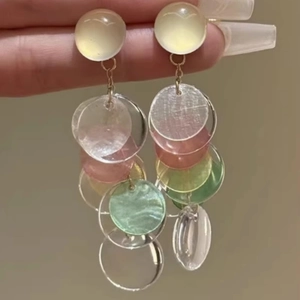 Detail of colorful acrylic charms and golden fringe on long beach style earrings