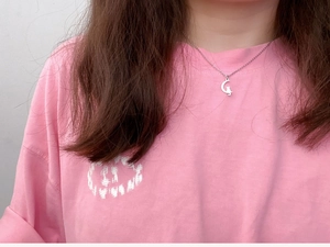 Close-up of a silver moon and cat pendant necklace worn on a woman's collarbone