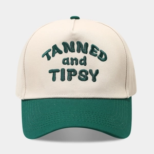 Detailed embroidery of TANNED and TIPSY text on a two-tone baseball cap crown