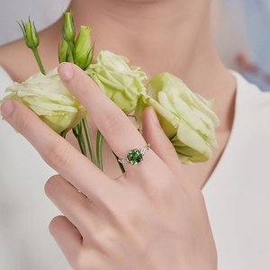Elegant green square-cut tourmaline-style ring on silver band with flower backdrop