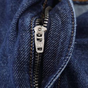 Macro d'une fermeture éclair YKK en argent et texture de tissu denim bleu foncé