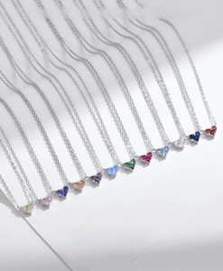 Detailed arrangement of twelve heart-shaped birthstone necklaces on silver chain