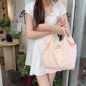 Detail of a pink floral tote bag with cartoon bunny print and woven checkered handles