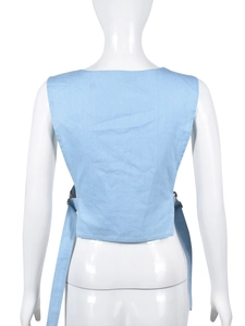 Détail des boucles métalliques et liens de serrage au dos du gilet en jean bleu clair