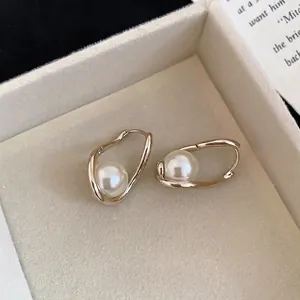 Boucles d'oreilles dorées vintage avec perles sur un plateau en velours beige