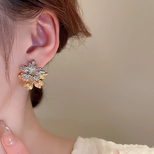 Detailed close-up of a model wearing a two-tone gold and silver petal tassel earring
