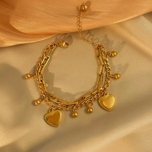 Gold double-layered stainless steel heart bracelet with beads on silk background