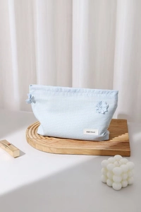 Detail view of light blue checkered makeup bag with 3D flower and brand logo tag