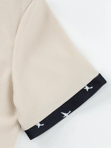 Close-up of beige waffle knit short sleeve with navy bird pattern jacquard cuff