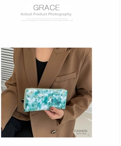 Close-up of mint green marble print long wallet with golden zipper held by a model