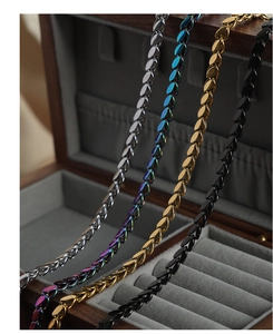 Detail of four titanium steel necklaces in silver, gold, rainbow and black in a jewelry box
