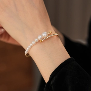 Macro detail of high-shine gold open bracelet with gradient pearls and crystal pavé inlay