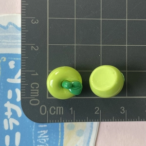 Vista macro di un mini ciondolo mela verde in resina da 1,5 cm per lavori fai da te