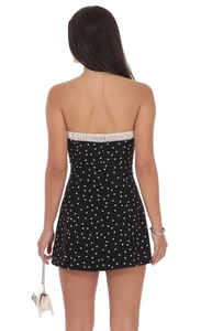 Détail d'une mini-robe dos nu à pois avec bordure blanche à volants à l'arrière