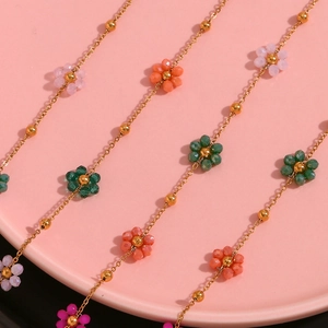 Macro shot of colorful floral beaded jewelry on a soft pink round display tray