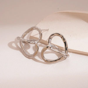 Macro shot of silver-toned twisted heart earrings with smooth polished metal texture