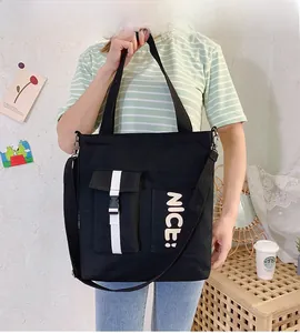 Detail of black canvas tote bag showing side buckle pocket and NICE printed text