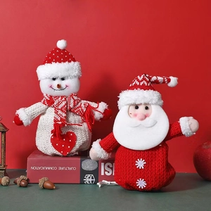 Close-up of knit Christmas gift bags featuring cartoon Santa and snowman with red scarves